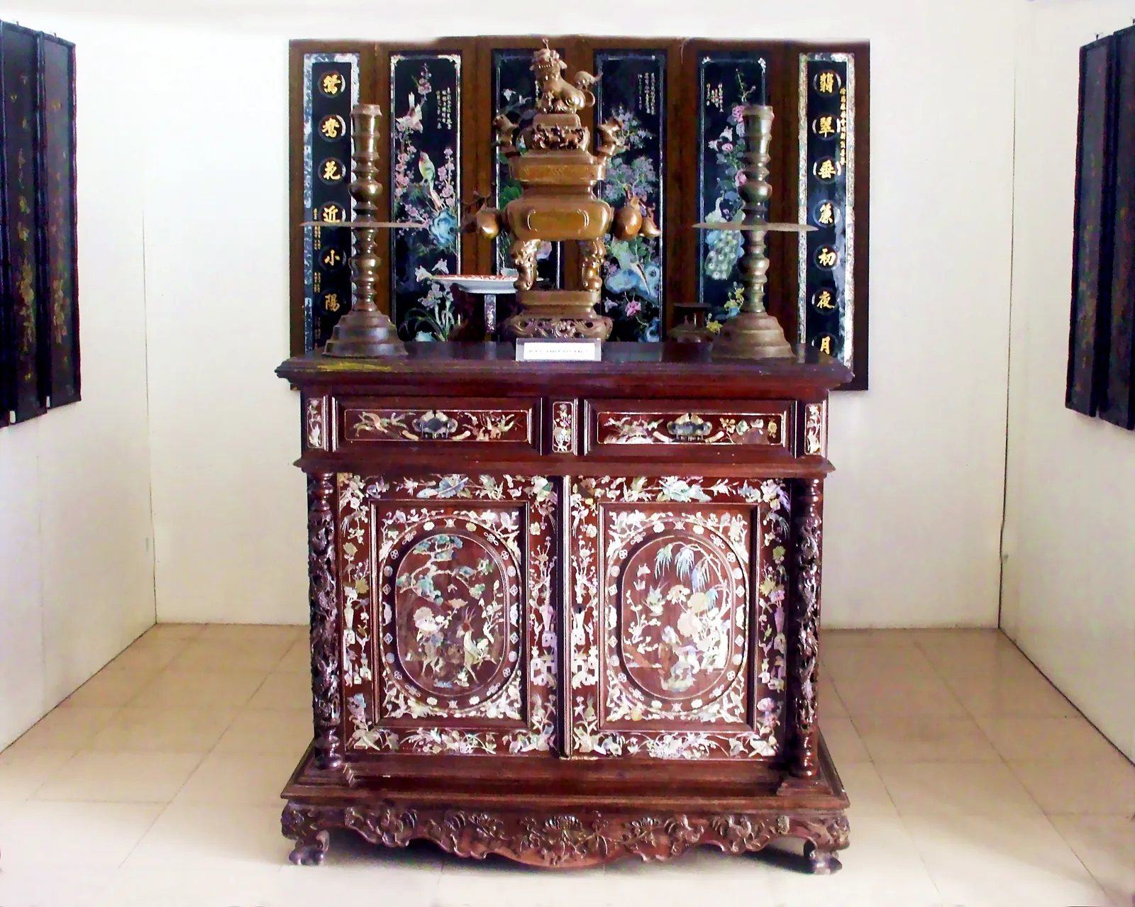Tủ thờ gỗ khảm xà cừ cùng lư hương đồng, đôi chân đèn và bộ liễn sơn mài khảm chữ Hán, trưng bày tại Bảo tàng An Giang